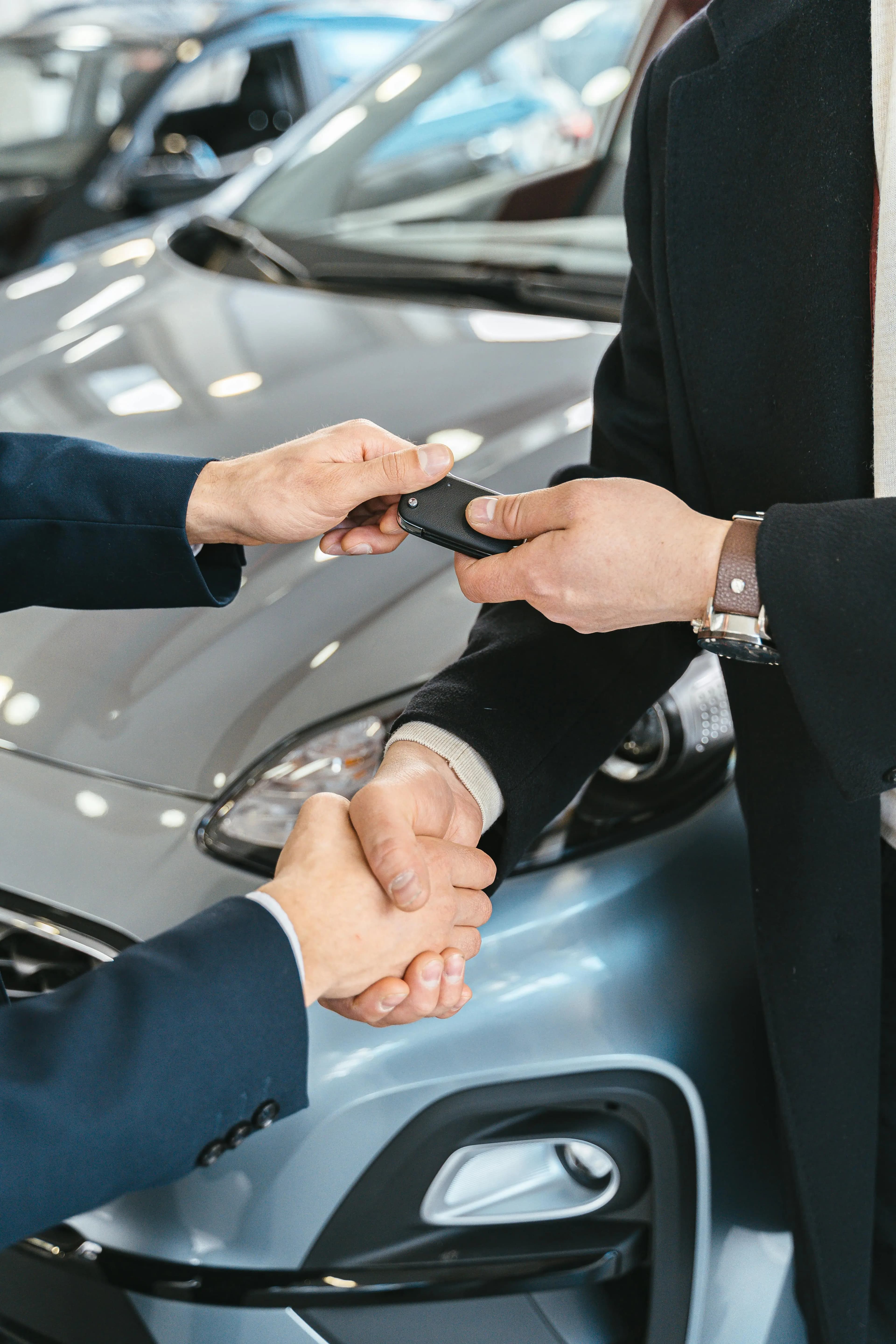 Salesperson handing car keys to a new owner with a handshake